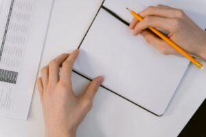 鉛筆でノートに確認事項を書き留める手元